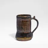 Ladi Kwali, Tankard, Glazed stoneware, tenmoku glaze with streaked iron decoration, the curved handle with a thumbpiece