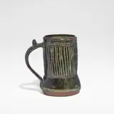 Ladi Kwali, Tankard, Glazed stoneware, tenmoku glaze with streaked iron decoration, the curved handle with a thumbpiece