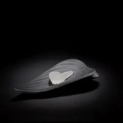 'Evolution' by Angela Jarman, 2003, Cast black glass, modelled as a leaf, surmounted by a cast and sandblasted caterpillar, offered May 2025