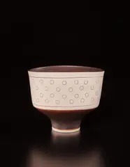 Oval bowl by Lucie Rie, circa 1970, Porcelain, manganese glaze, with circular impressed designs inlaid with glaze, sold Dec 2017