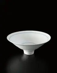 Flaring footed bowl by Lucie Rie, circa 1978, Porcelain, matte white glaze over concentric inlaid blue lines repeated inside and out, sold Dec 2016