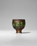 Lucie Rie, Small Footed Cup, porcelain, decorated with green glaze and a golden manganese running down the rim, impressed with artist's monogram