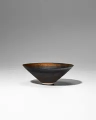 Small Conical Bowl by Lucie Rie, porcelain decorated with golden manganese bands, with sgraffito design radiating from the center, impressed with artist', sold Jun 2025