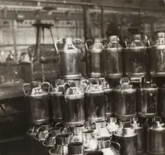 Germaine Krull, Cans for the delivery of milk, Paris c. 1930, from the series 'Les Ouvrières des Paris, Vintage silver print on double-weight semi-matte paper, in very good condition. Photographer's copyright stamp, "Agentur Schostal, Wien IV., Starhemberggasse 26" agency stamp, annotation "Ces hauts ré