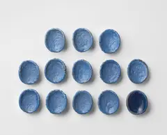 Thirteen buttons by Lucie Rie, circa 1945-1950, Earthenware, blue glazes, sold Oct 2024