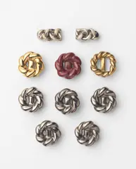 Ten knotted buttons by Lucie Rie, circa 1945-1950, Stoneware, silver, gold, cream and plum glazes, sold Oct 2024