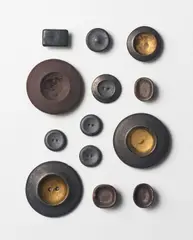 Thirteen buttons by Lucie Rie, circa 1945-50, Earthenware, brown, black, gold and manganese glazes, sold Oct 2024