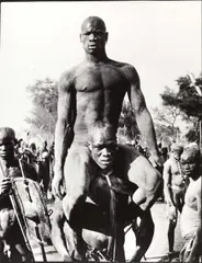George Rodger, Fellow tribesman carries victorious Nuba wrestler, Kordofan, Sudan 1949, 1949, Gelatin silver print, printed 1989 on double-weight semi-matte paper