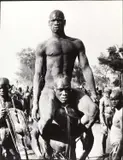 George Rodger, Fellow tribesman carries victorious Nuba wrestler, Kordofan, Sudan 1949, 1949, Gelatin silver print, printed 1989 on double-weight semi-matte paper