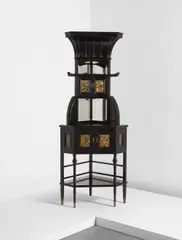 Edward William Godwin, Corner cabinet, circa 1873, Ebonized mahogany, beveled mirrored glass, inset gilt-decorated panels, brass