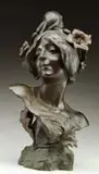 Cadet-Julien Causse, Floreal-June, Bronze sculpture bust of a woman with flowers in her hair on a naturalistic base with leaf decoration. Dark brown patina