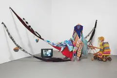 John Bock, Trial of Deutsche Bank, 2002-2003, mixed media installation (17:33 min DVD, clothing elements, lawn mower with wooden armature and puppet, newspaper, beads, yarn)