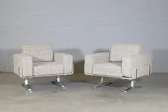 William Plunkett, Pair of club armchairs, c.1970, each with cream upholstery and raised on aluminium supports