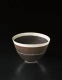 Deep bowl by Lucie Rie, circa 1956, Porcelain, manganese and white glazes, with a deep band of fine sgraffito design, sold Dec 2013