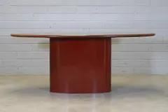Max Clendinning, Desk, 1980, the brass-inlaid oval mahogany top raised on a red metal pedestal support