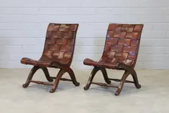 Pierre Lottier, Pair of Spanish leather low chairs, each with a leather-upholstered curved seat and raised on 'X' frame supports united by stretchers