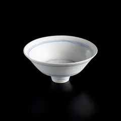 Footed bowl by Lucie Rie, circa 1978, Porcelain, matte white glaze with concentric inlaid blue lines repeated inside and out, sold Apr 2025