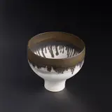 Footed bowl by Lucie Rie, circa 1980, Porcelain, pure matt white glaze with a golden manganese rim, sold Apr 2023