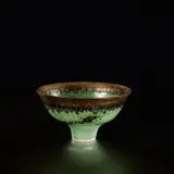 Footed bowl by Lucie Rie, circa 1982, Porcelain, green glaze with golden bronze running rim, sold Nov 2023