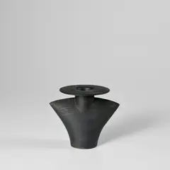 'Torso' bottle with disc top by Hans Coper, circa 1970, Stoneware, black glaze over a textured and incised body, sold Nov 2023