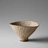 Deep oval bowl with fluted exterior by Lucie Rie, circa 1980, Stoneware, deeply pitted white glaze with integral speckle, sold Nov 2023