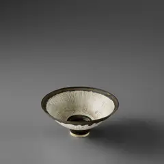 Small footed bowl by Lucie Rie, circa 1978, Porcelain with radiating inlaid and sgraffito lines, golden manganese foot and lip, sold Nov 2023