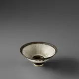 Small footed bowl by Lucie Rie, circa 1978, Porcelain with radiating inlaid and sgraffito lines, golden manganese foot and lip, sold Nov 2023