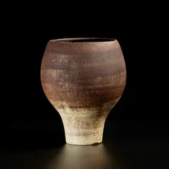 Early footed pot by Hans Coper, circa 1953, Stoneware, porcelain slip and engobes over a textured body, the interior with a manganese glaze, sold May 2022