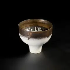 Footed bowl by Lucie Rie, circa 1980, Porcelain, pure matt white glaze with a golden manganese rim, sold May 2022
