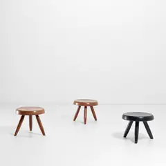 Three 'Berger' stools by Charlotte Perriand, circa 1953, Two in cedar and one in ebonised cedar, sold May 2022