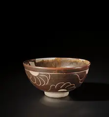 Bowl with chrysanthemum design by Bernard Leach, 1937, Stoneware, layered tenmoku over white glazes with the design carved through, sold Nov 2021