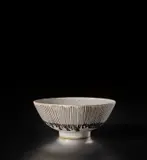 Footed bowl by Lucie Rie, circa 1955, Stoneware, white glaze with a delicate oatmeal speckle, the exterior with inlaid managanese lines, sold Nov 2021