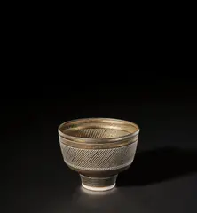 Lucie Rie, Footed bowl, circa 1975, Porcelain, bright golden glaze with horizontal bands of diagonal sgraffito designs repeated inside and out