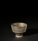 Footed bowl by Lucie Rie, circa 1975, Porcelain, bright golden glaze with horizontal bands of diagonal sgraffito designs repeated inside and out, sold Nov 2021