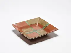 Square Dish by Shoji Hamada, 1965, stoneware, persimmon and wood ash glaze with a trailed seigi green cross, sold Jul 2021