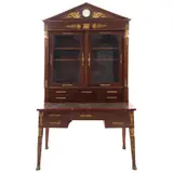 Escritorio Con Vitrina, SIGLO XX, Talla en madera a dos cuerpos con aplicaciones en bronce. Remate a manera de frontón triangular con reloj. Cubierta de piel y soportes a manera de garra. Decorado con mascarones, victorias y esfinges