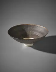 Footed bowl by Lucie Rie, circa 1975, Porcelain, manganese glaze with radiating sgraffito design, white glazed foot and well, sold Apr 2018