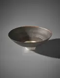 Footed bowl by Lucie Rie, circa 1975, Porcelain, manganese glaze with radiating sgraffito design, white glazed foot and well, sold Apr 2018