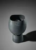 Pot on cylindrical foot by Hans Coper, circa 1974, Stoneware, black glaze over incised designs, the interior with a cylindrical stem-holder, sold Apr 2018