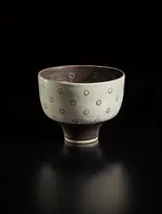 Footed bowl by Lucie Rie, late 1970s, Porcelain, manganese and pale blue glaze, circular impressed designs inlaid with glaze are repeated freehand in sgraffit, sold Oct 2018
