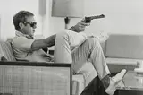 John Dominis, Steve McQueen aims a pistol in his living room, California, 1963, Gelatin silver print, printed later, flush-mounted