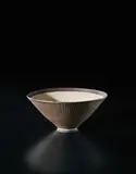 Conical bowl by Lucie Rie, circa 1972, Porcelain, golden manganese glaze with sgraffito on the exterior, the interior unglazed with inlaid radiating design, sold Sep 2017