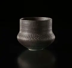 Pot by Lucie Rie, circa 1965, Porcelain, flowing manganese glaze with bands of sgraffito circles around the shoulder, sold Sep 2017