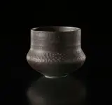 Pot by Lucie Rie, circa 1965, Porcelain, flowing manganese glaze with bands of sgraffito circles around the shoulder, sold Sep 2017