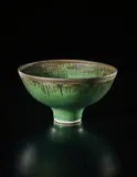 Footed bowl by Lucie Rie, circa 1980, Porcelain, deep green glaze with golden lip, sold Sep 2017
