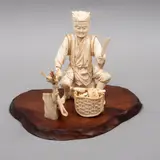 Okimono de Vendedor de Temakis, JAPÓN, SIGLO XX, Talla en hueso, detalles en tinta negra, con base de madera