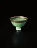 Footed bowl by Lucie Rie, circa 1978, Porcelain, bottle green glaze with golden lip and manganese speckle, sold Oct 2015