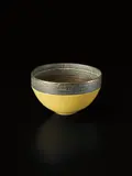 Bowl by Lucie Rie, circa 1976, Porcelain, pitted yellow and golden manganese glazes. A deep band of sgraffito grid repeated inside and out, sold Oct 2015
