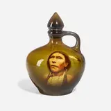 Cheyenne, Feather Wolf (Fine Standard Glaze portrait whiskey jug with stopper) by Sadie Markland for Rookwood Pottery, sold Nov 2023