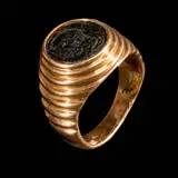 An 18k Ring with Silver Coin, Untitled, Crafted in 18k yellow gold, the ring features a silver coin set into a boldly domed band. <br> The ring is detailed with a classic ribbed design along the shoulders. <br> Weighs 13.0 grams
